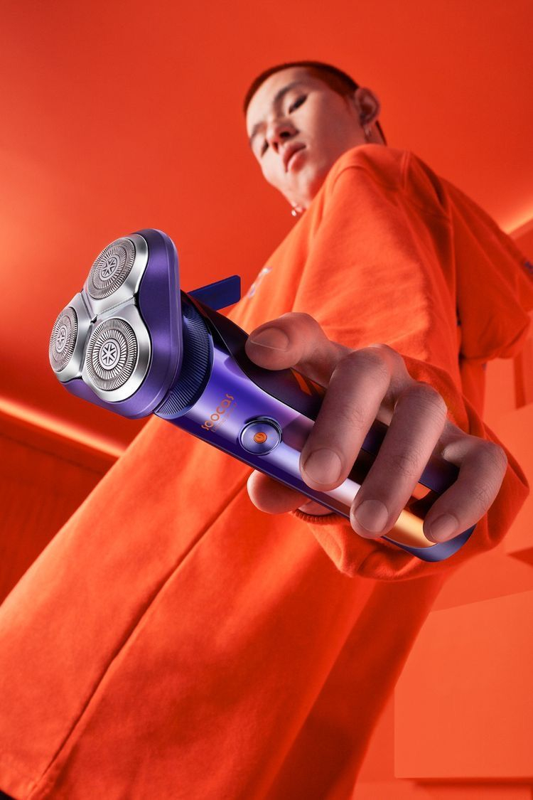 Modern Electric Shaver Showcase — A bold editorial product photograph featuring a modern electric rotary shaver held toward the camera from an extreme low angle
