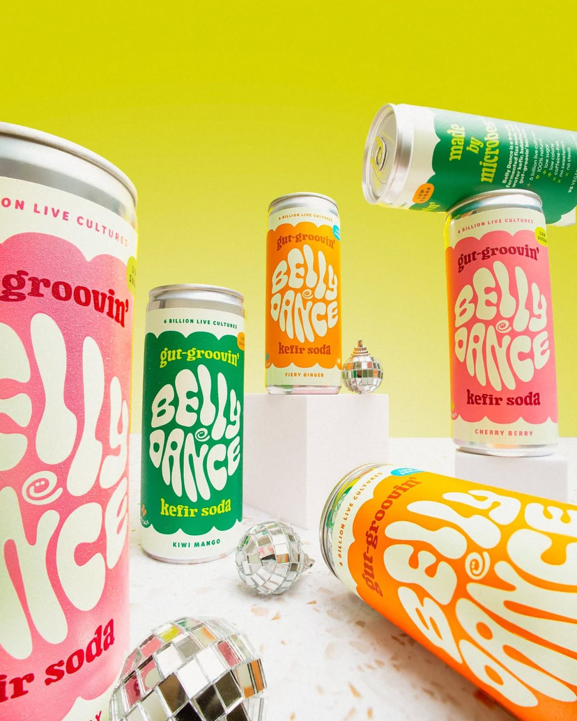 Retro Disco Beverage Showcase — A bold and playful studio product photograph featuring multiple colorful kefir soda cans with retro wavy typography branding. Th