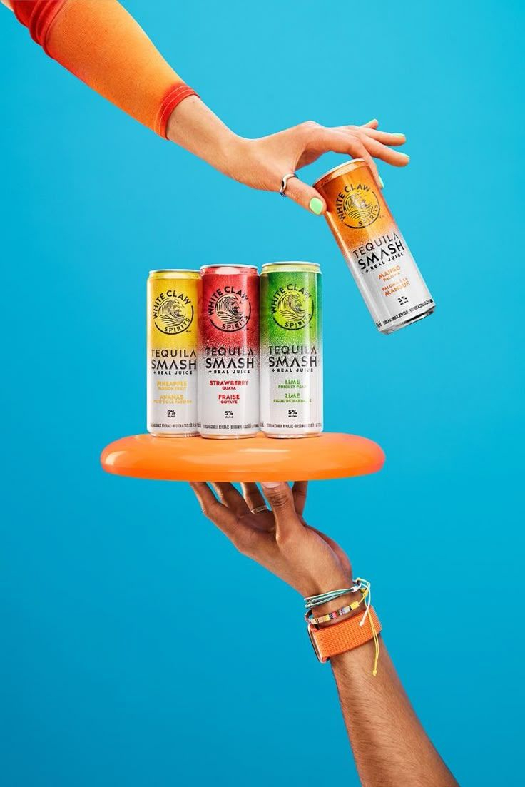 Vibrant Tequila Smash Product Showcase — A vibrant lifestyle product photograph featuring four slim tequila cocktail cans displayed on a floating round orange t